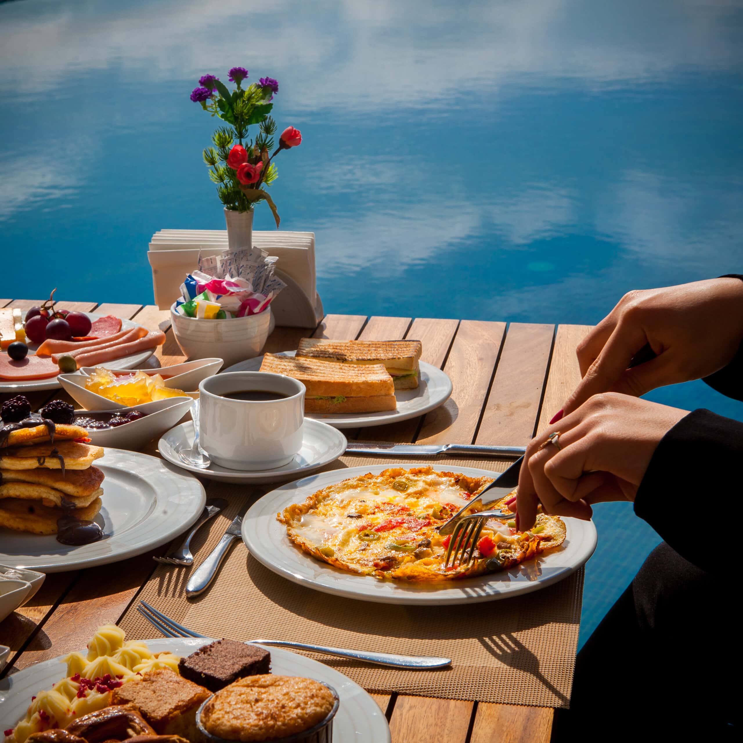 Side view served table girl eats omelet with vegetables, pancakes food with chocolate, cake on a wooden table